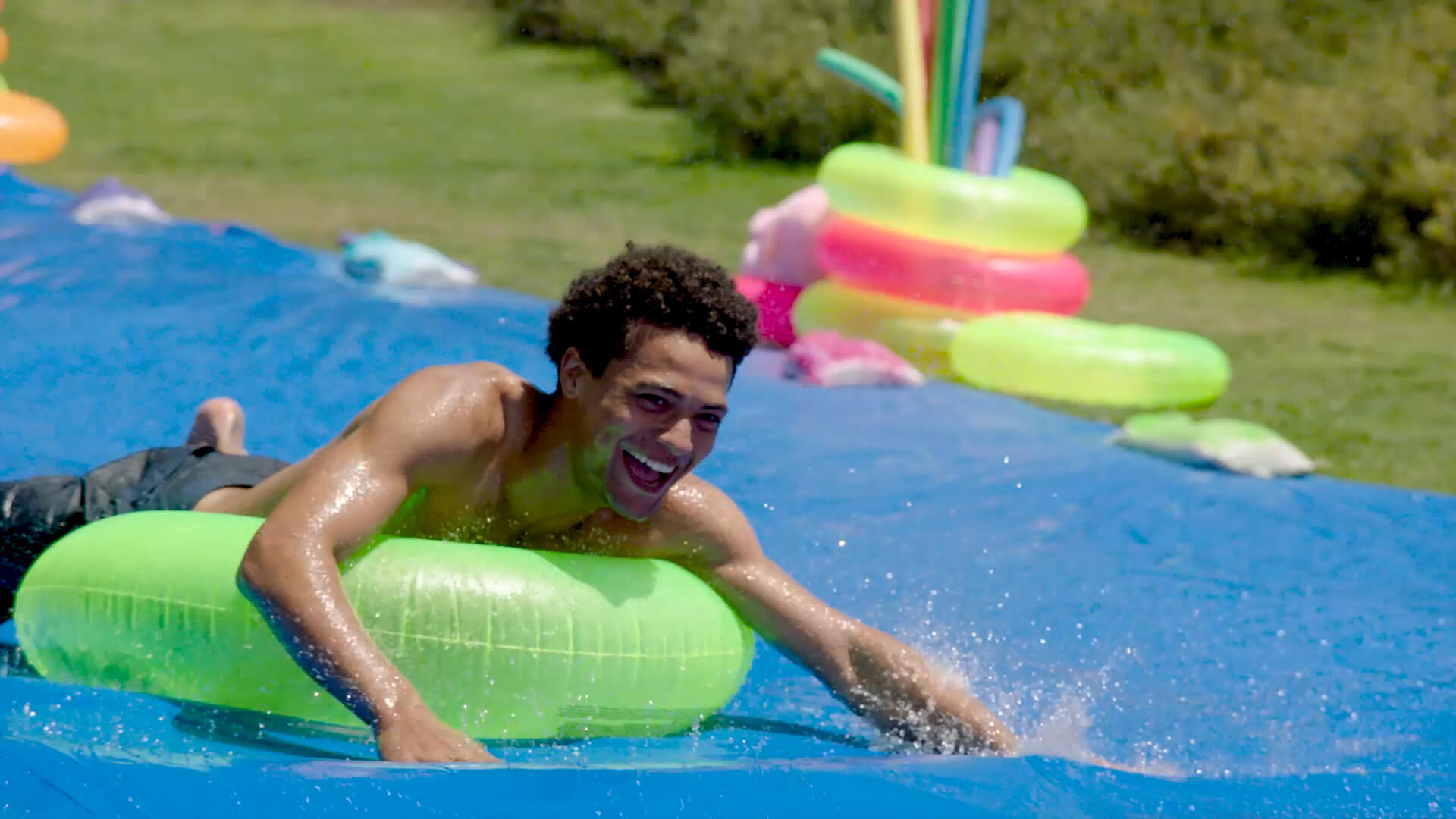 a male rides an inner tube down a water slide for Hollister Co.
